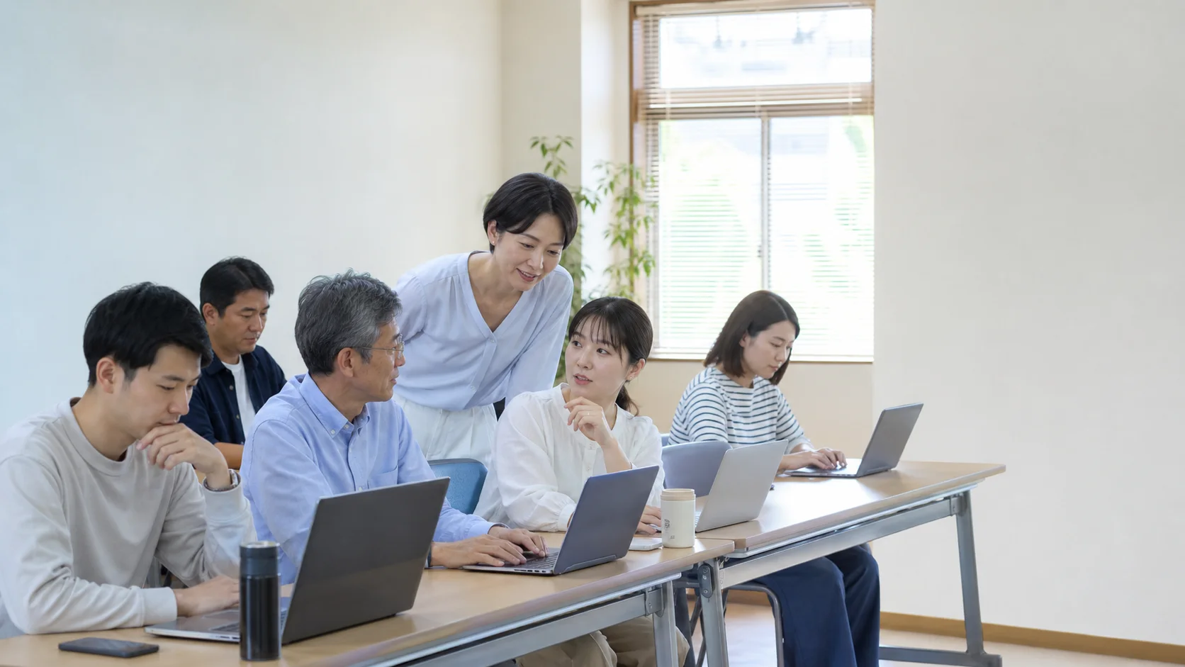 少人数でテーブルを囲み、それぞれのパソコンで作業する様子